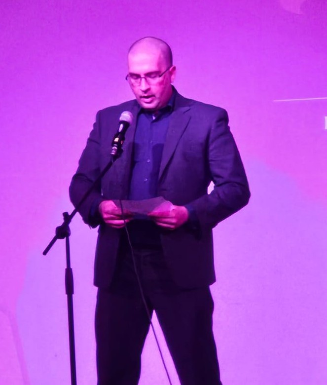 Male performer on stage, engaged in a live performance, connecting with the audience through his music.