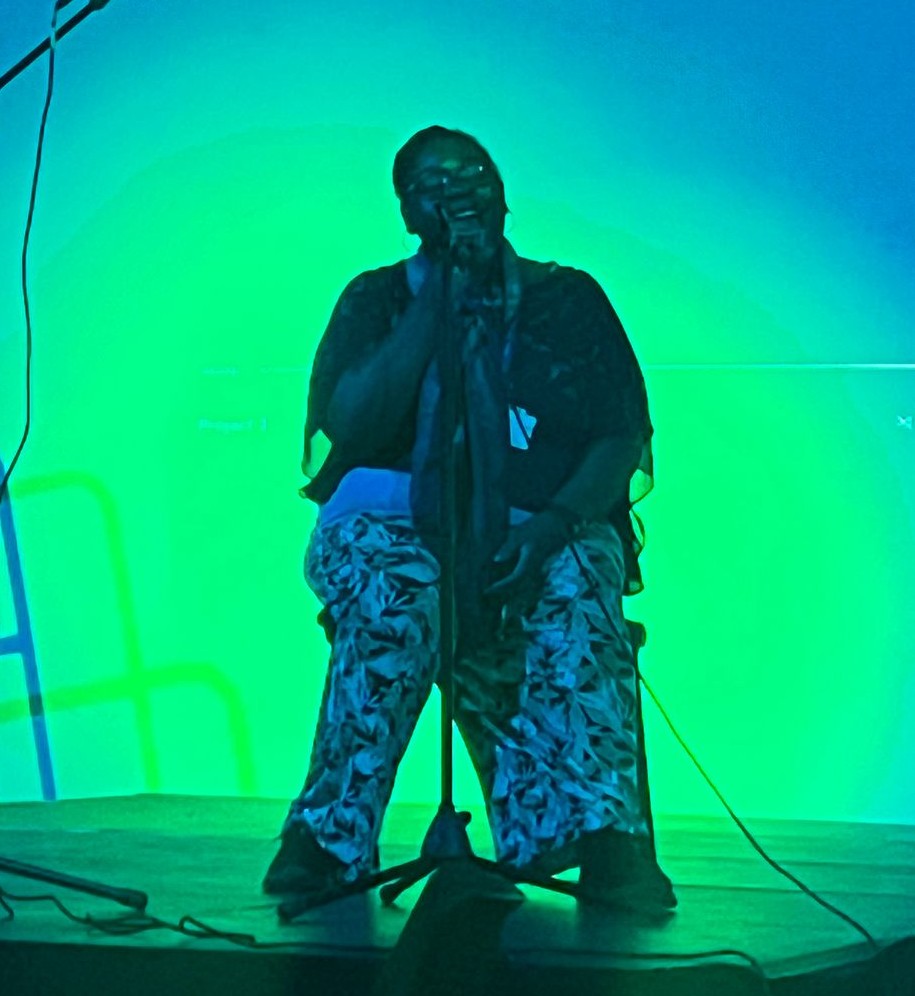 Soulful singer seated and performing with emotion and depth.
